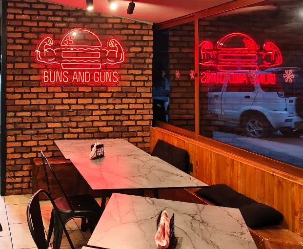 Tables under the red Buns and Guns neon logo